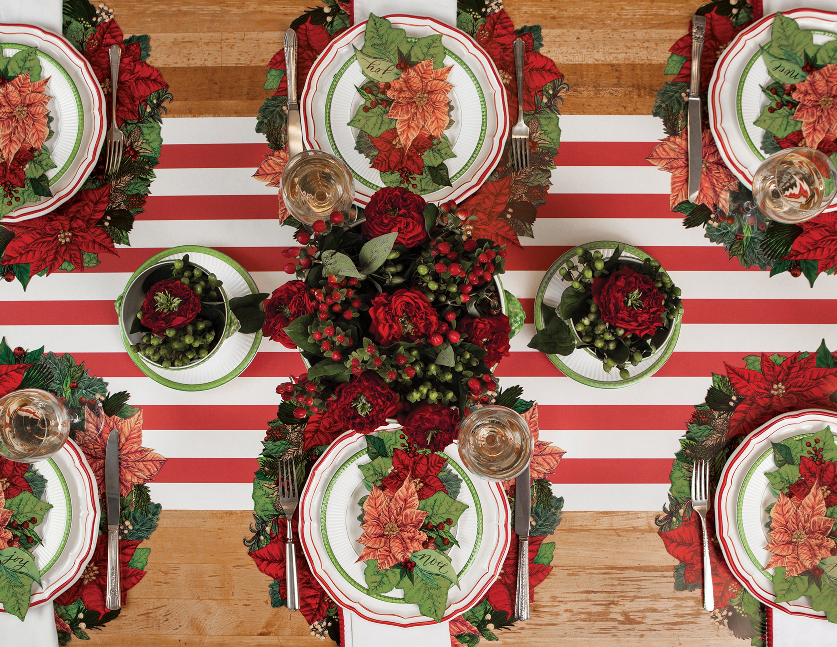 Top-down view of a Christmas table setting featuring Poinsettia Table Accents resting on the plates.