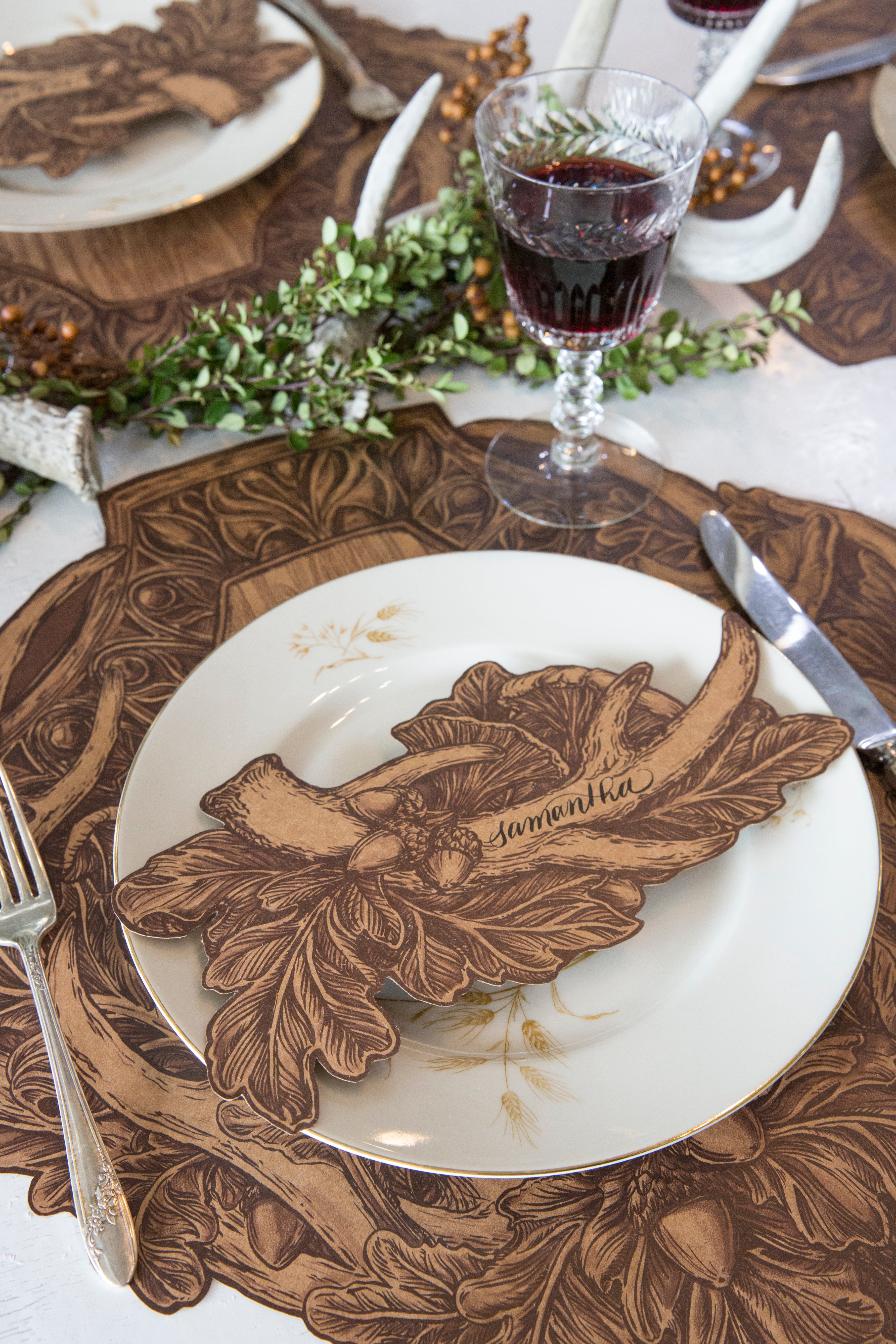 An Antler Table Accent with "Samantha" written on the antler resting on the plate of a rustic place setting.