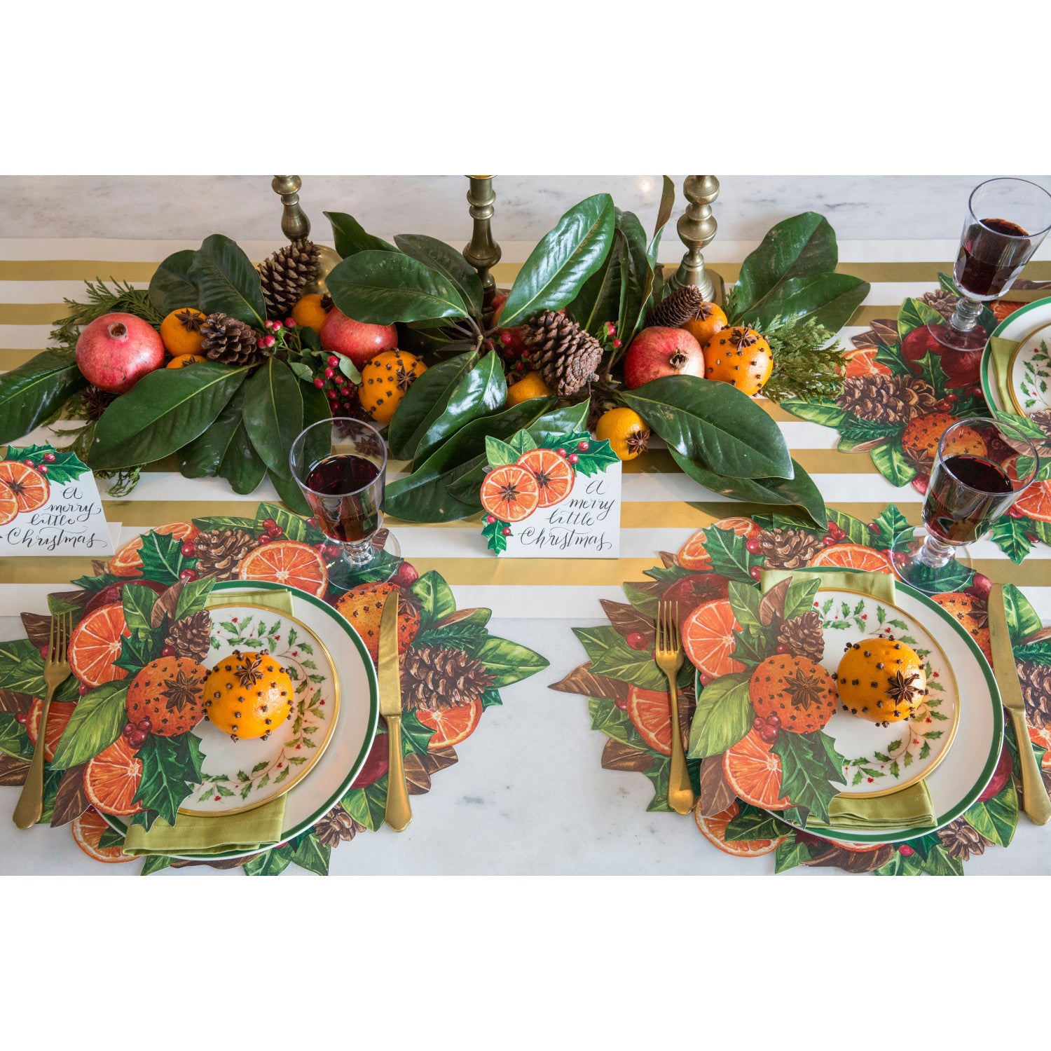 A festive winter tablescape featuring Pomander Table Accents resting on each plate.