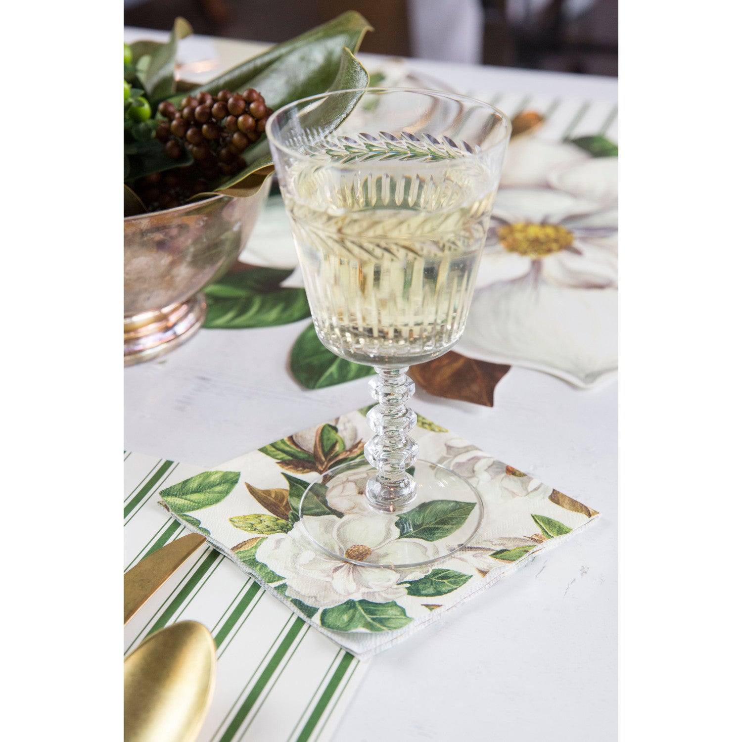 A glass of white wine on a Magnolia Cocktail Napkin, as part of an elegant tablescape.