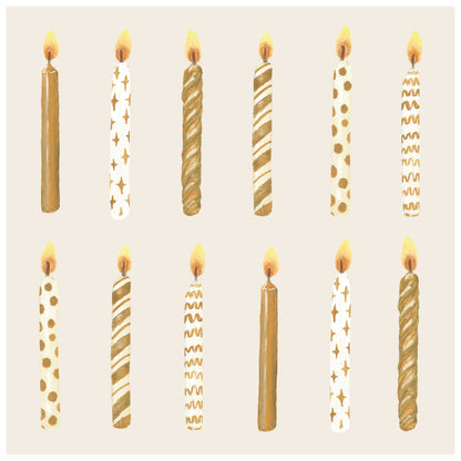 A square, cream-colored cocktail napkin featuring a dozen differently designed gold and white lit birthday candles evenly spaced in two rows.