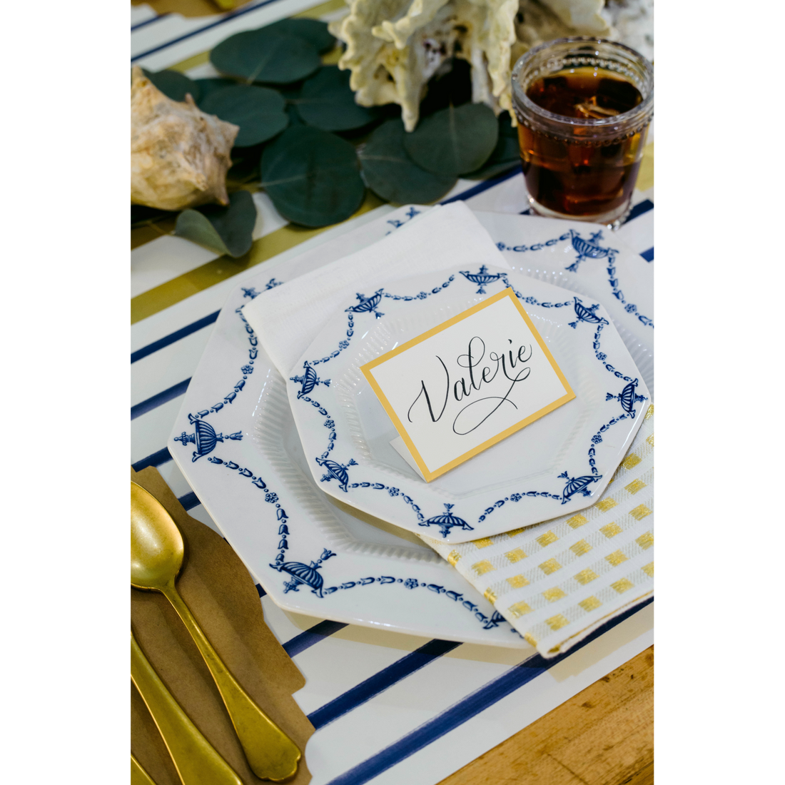 An elegant place setting featuring a Gold Foil Frame Place Card labeled &quot;Valerie&quot; standing on the plate.