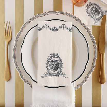 An elegant place setting featuring a Majestic Guest Napkin centered on the plate, and a Majestic Crest Napkin under the water glass, from above.
