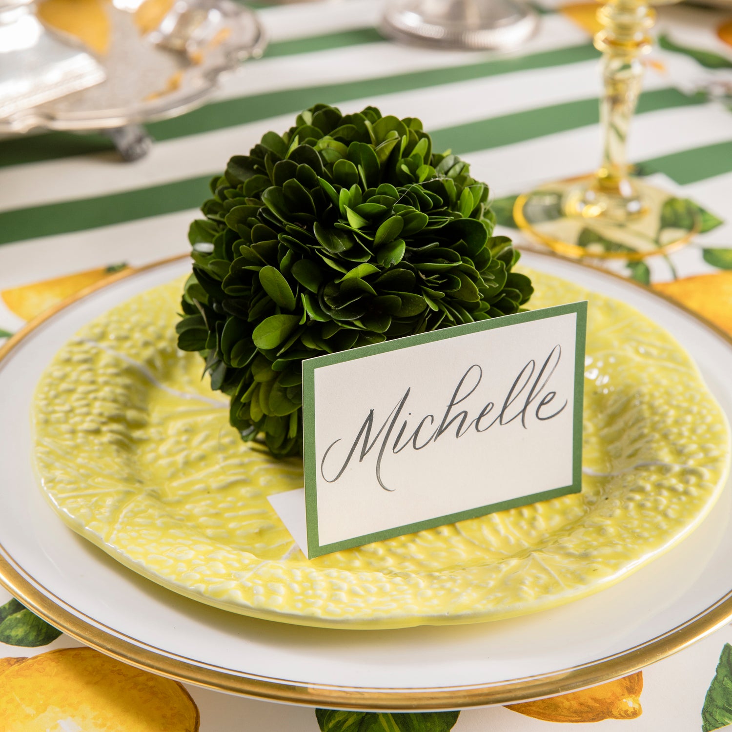 A Preserved Boxwood Sphere with a place card and lemons on it, painstakingly assembled by masterful artists, made by Accent Decor.
