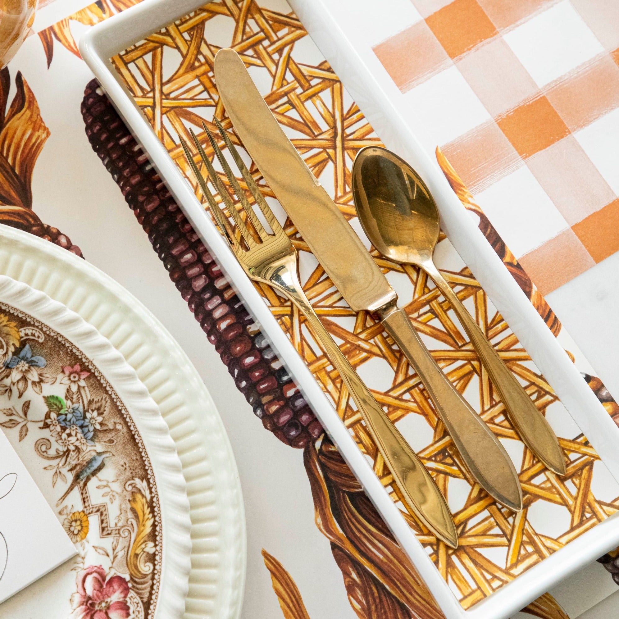 Close-up of a flatware tray lined with a rectangle cut from a Rattan Weave Placemat, used in an elegant place setting.