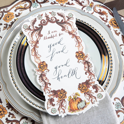 Close-up of an elegant Thanksgiving place setting featuring an &quot;I Am Thankful For&quot; Table Accent resting on the plate.
