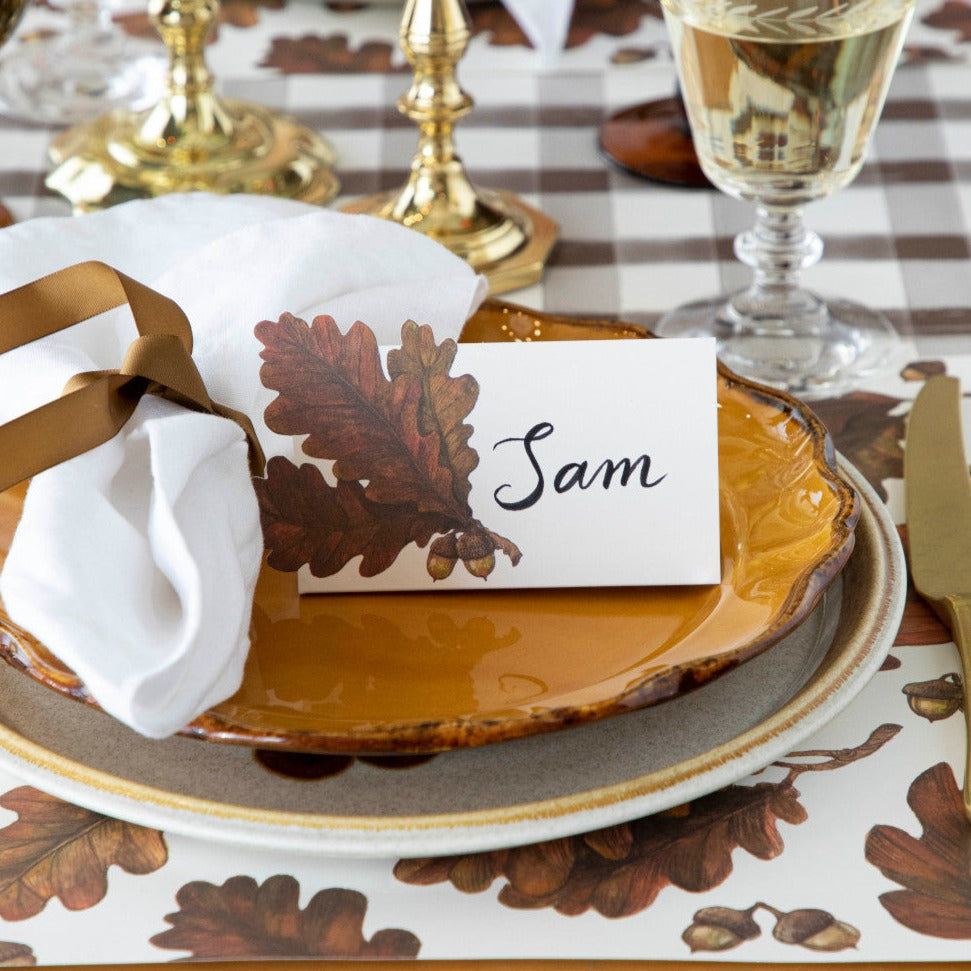 An elegant fall-themed place setting featuring an Autumn Leaves Place Card reading "Sam" on the plate.