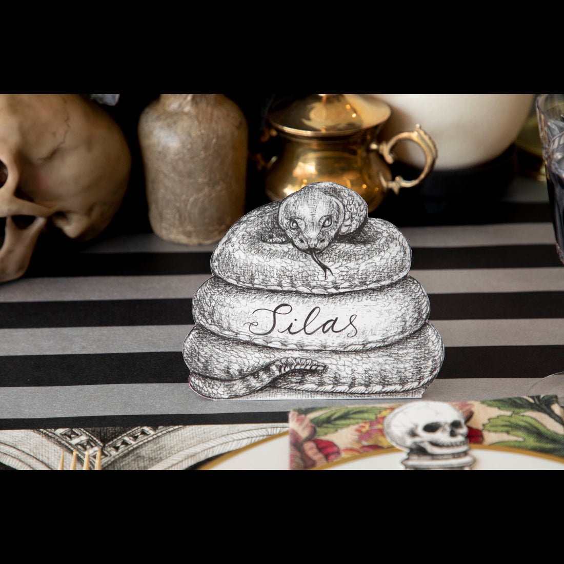 A Coiled Snake Place Card reading &quot;Silas&quot; standing on a spooky Halloween-themed tablescape.