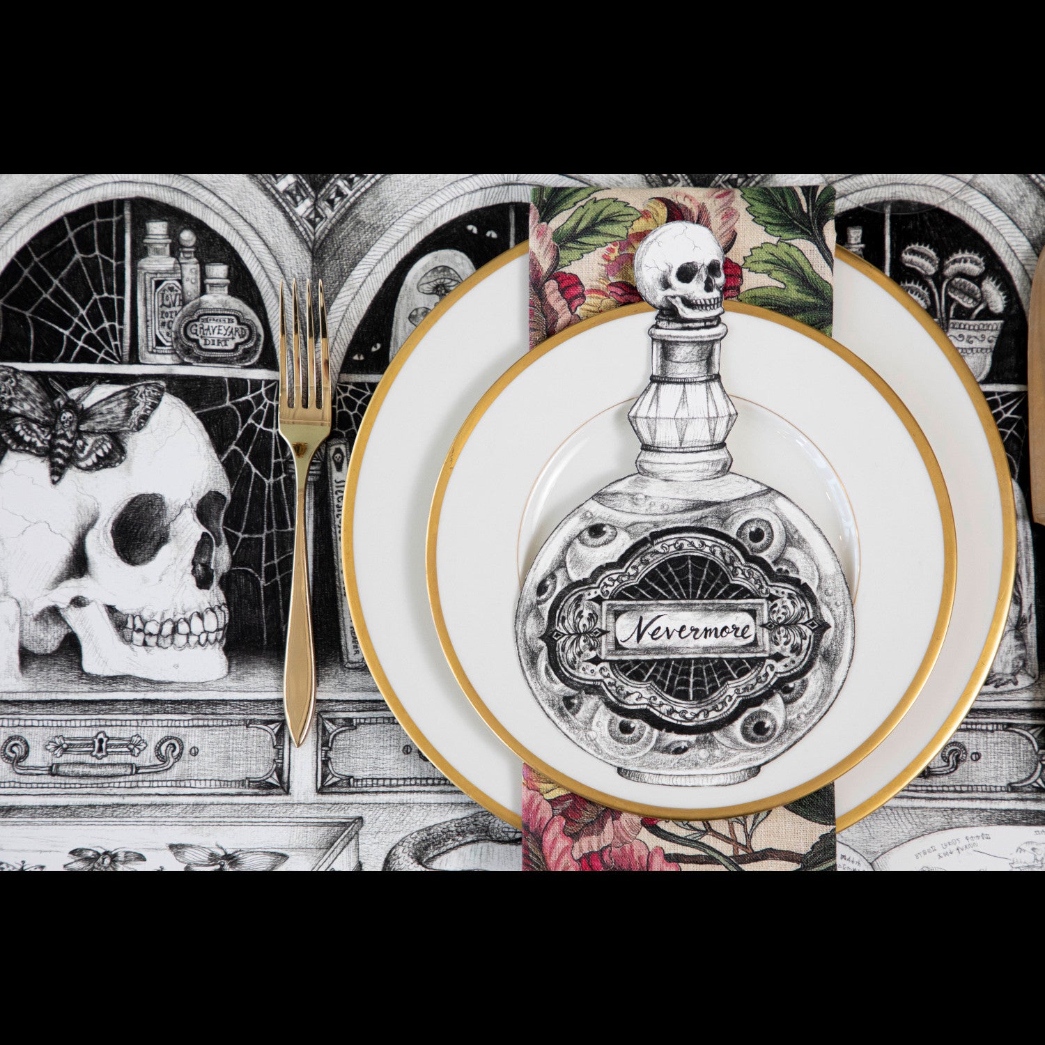 A spooky Halloween-themed place setting featuring a Poison Bottle Table Accent with &quot;Nevermore&quot; written on the label resting on the plate.