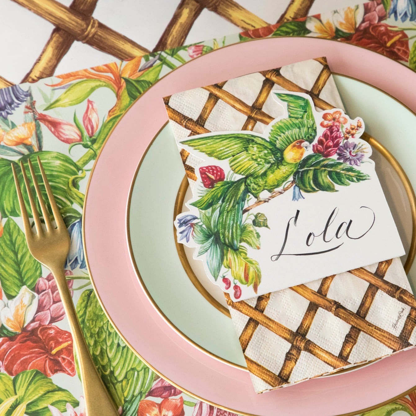 A vibrant tropical-themed place setting featuring a Parrot Place Card labeled &quot;Lola&quot; laying flat on the plate.