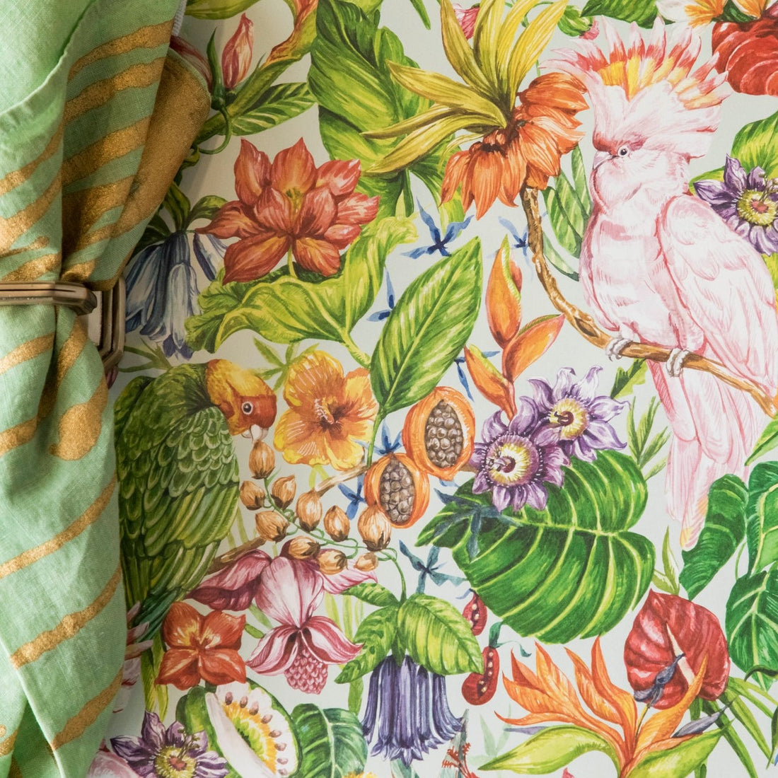 A close-up of the Birds of Paradise Placemat, showing the detailed floral design and the pick cockatoo, with a fabric napkin on the left side. 