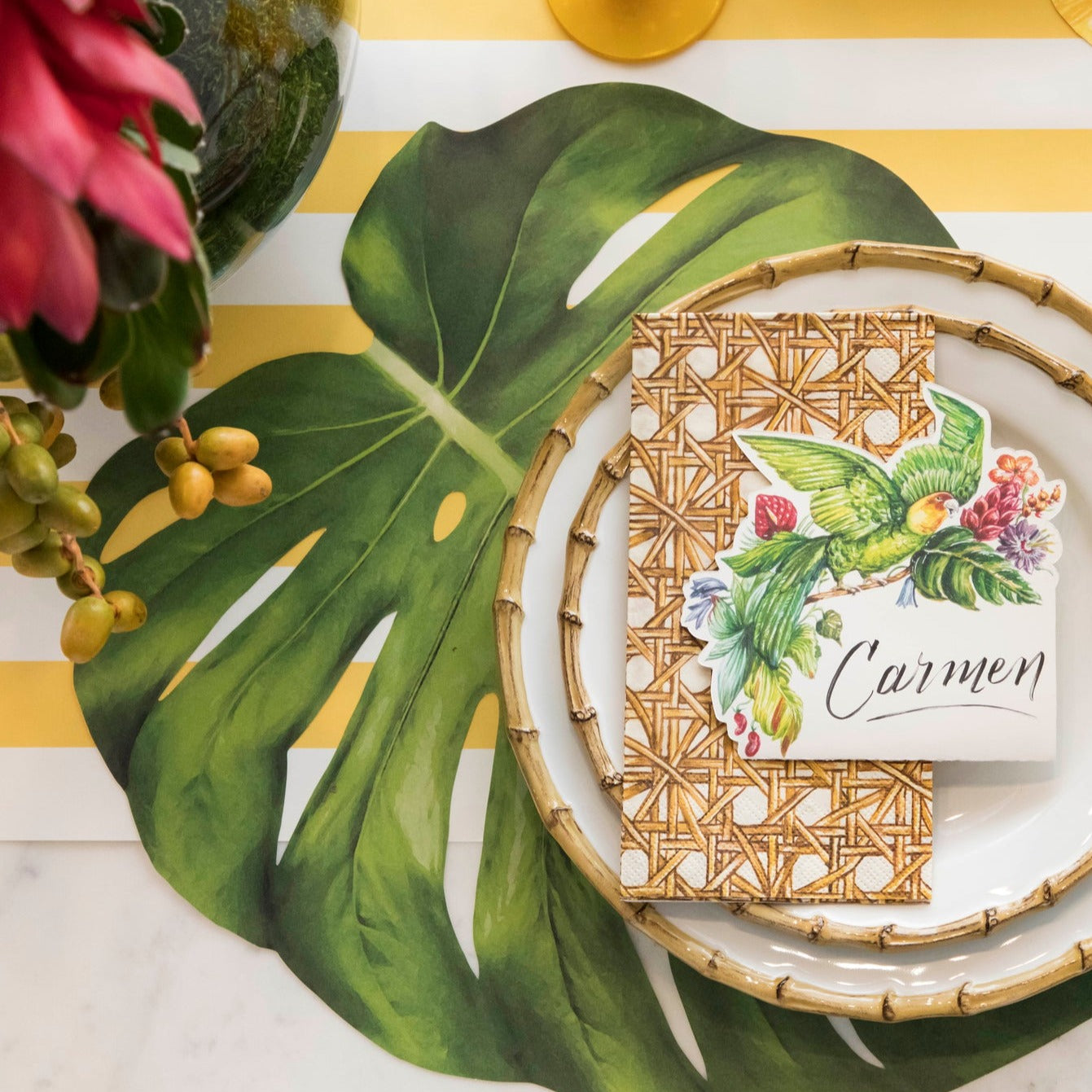 An elegant table setting adorned with tropical Die-cut Monstera Placemats from Hester & Cook, complemented by colorful flowers.