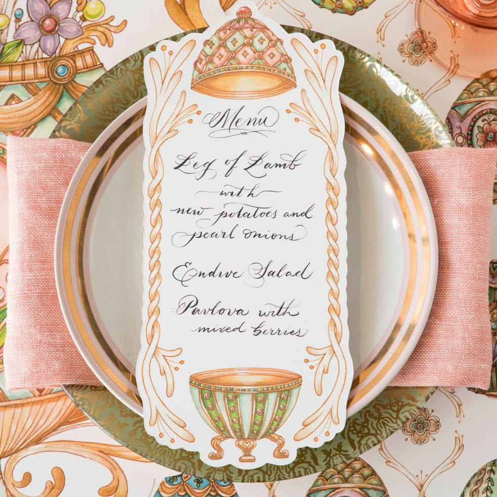 Close-up of an Exquisite Egg Table Card with a menu written on it in beautiful script resting on the plate of an elegant Easter place setting.