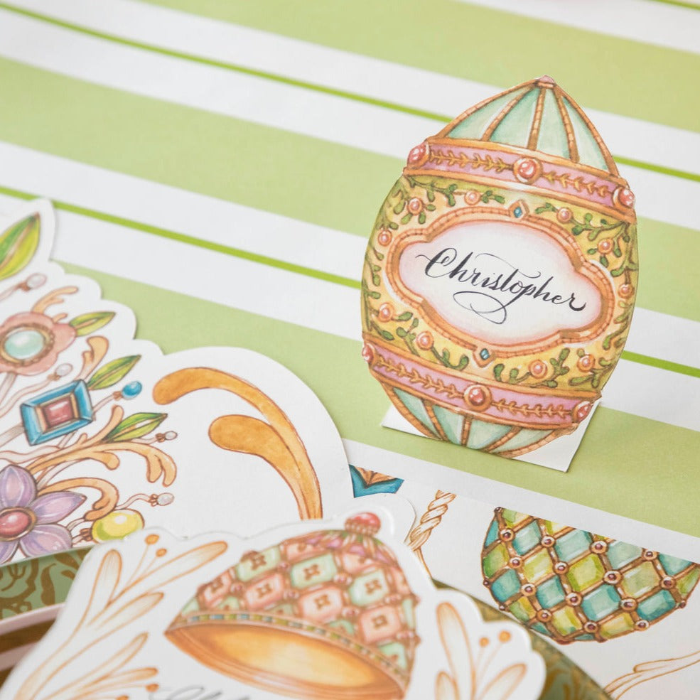 An Exquisite Egg Place Card labeled &quot;Christopher&quot; standing by the plate of an elegant Easter themed place setting.