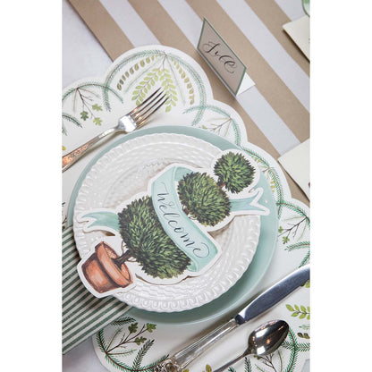 An elegant place setting featuring a Topiary Table Accent with &quot;Welcome&quot; written on the ribbon resting on the plate.