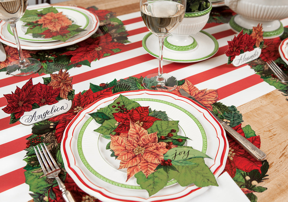 A Christmas table setting featuring Poinsettia Table Accents resting on the plates.