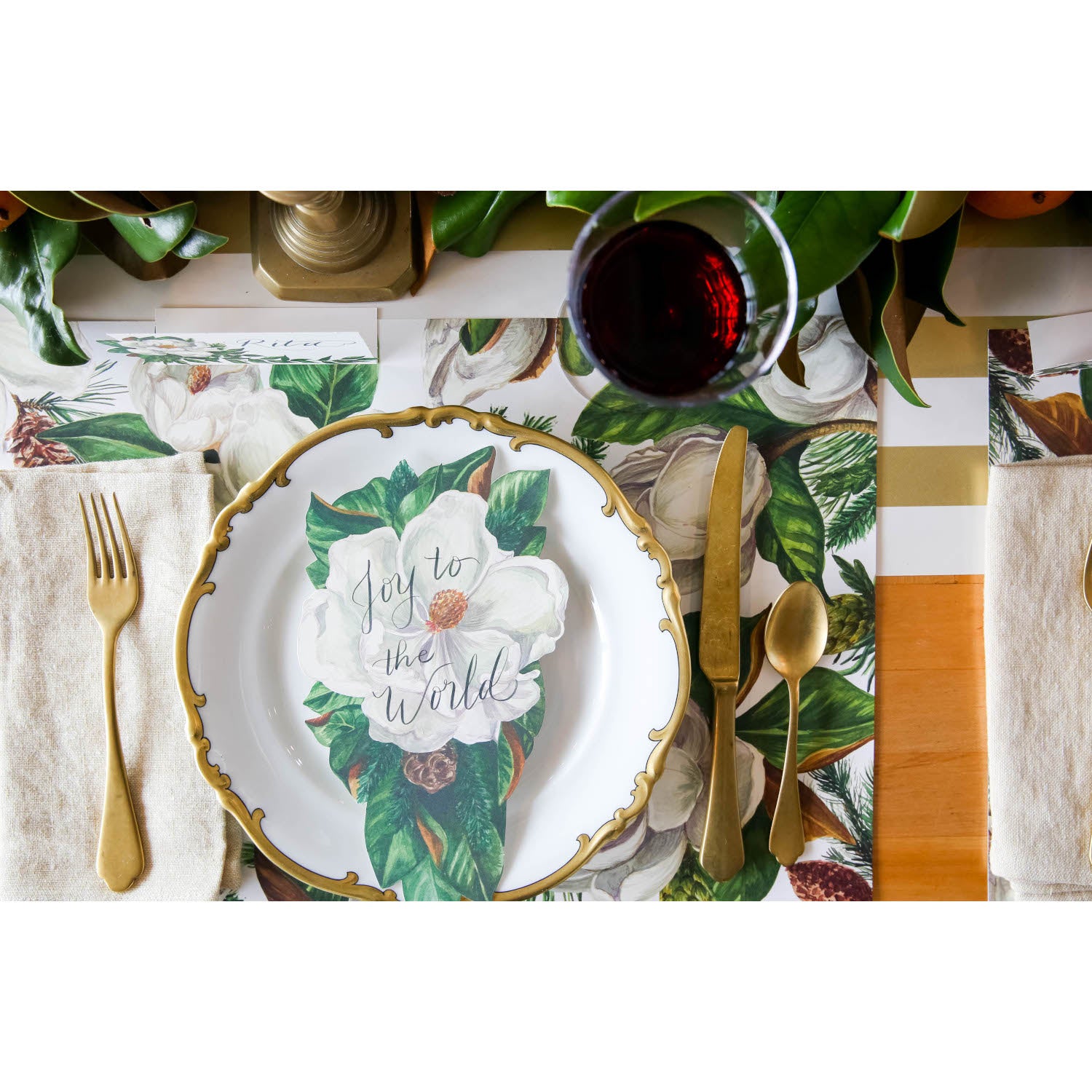 An elegant Christmas place setting featuring a Magnolia Table Accent with "Joy to the World" written in beautiful script resting on the plate.