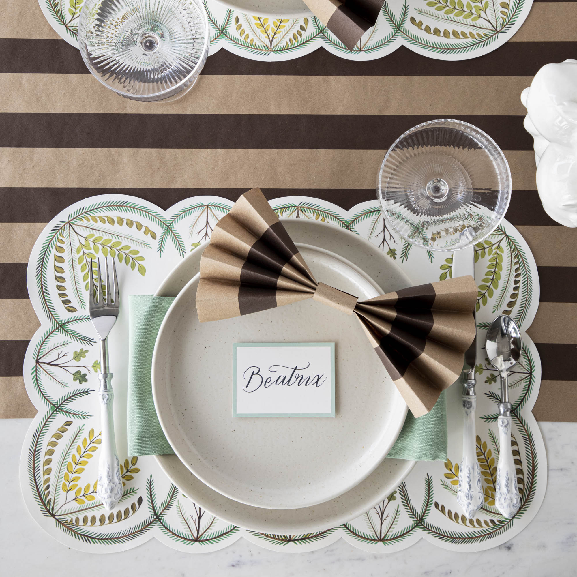 The Kraft Brown Classic Stripe Runner under an elegant table setting, plates adorned with crafted bows made from cut pieces of the runner, from above.