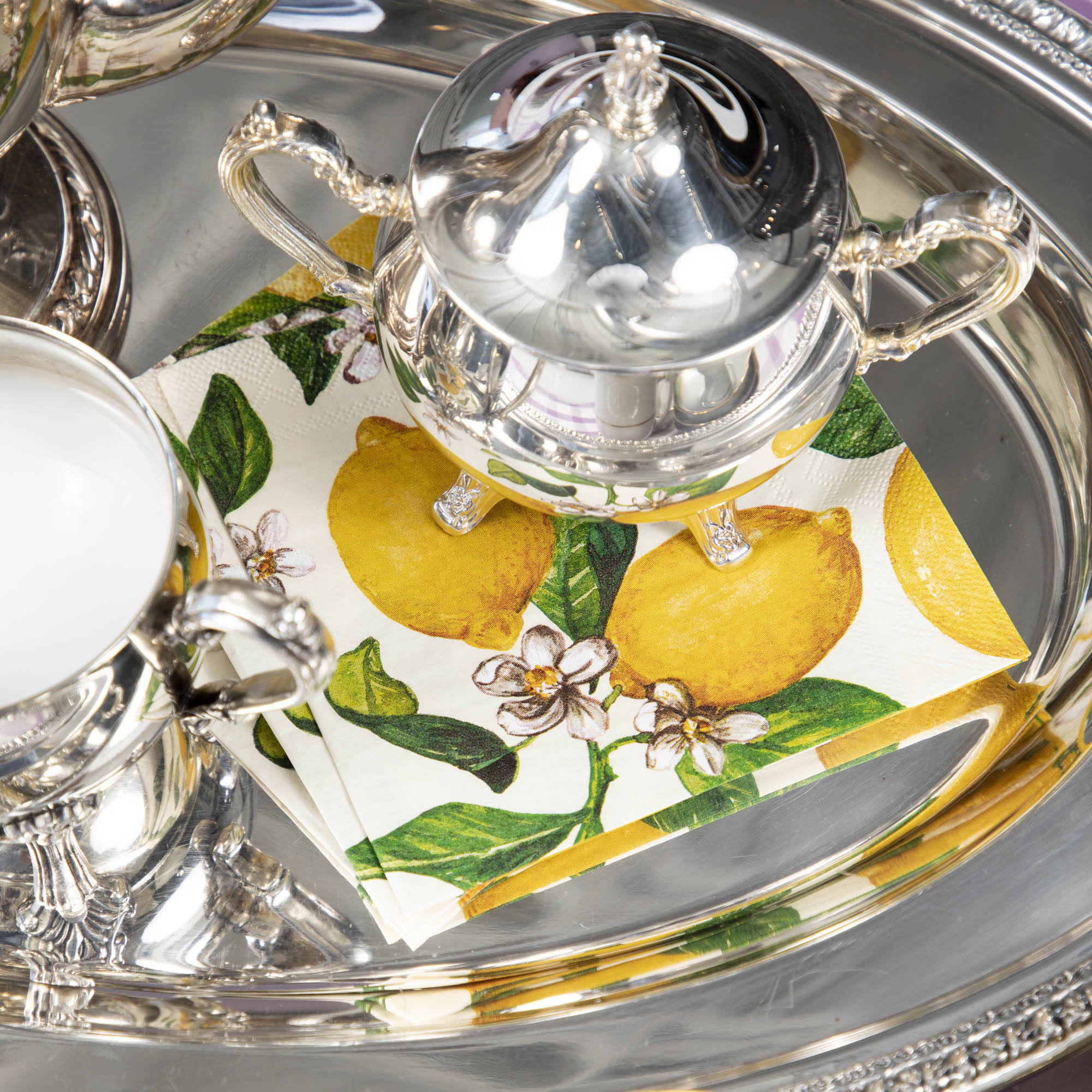 A silver tray with Hester & Cook Lemons Napkins on it, adding a pop of color to any occasion.