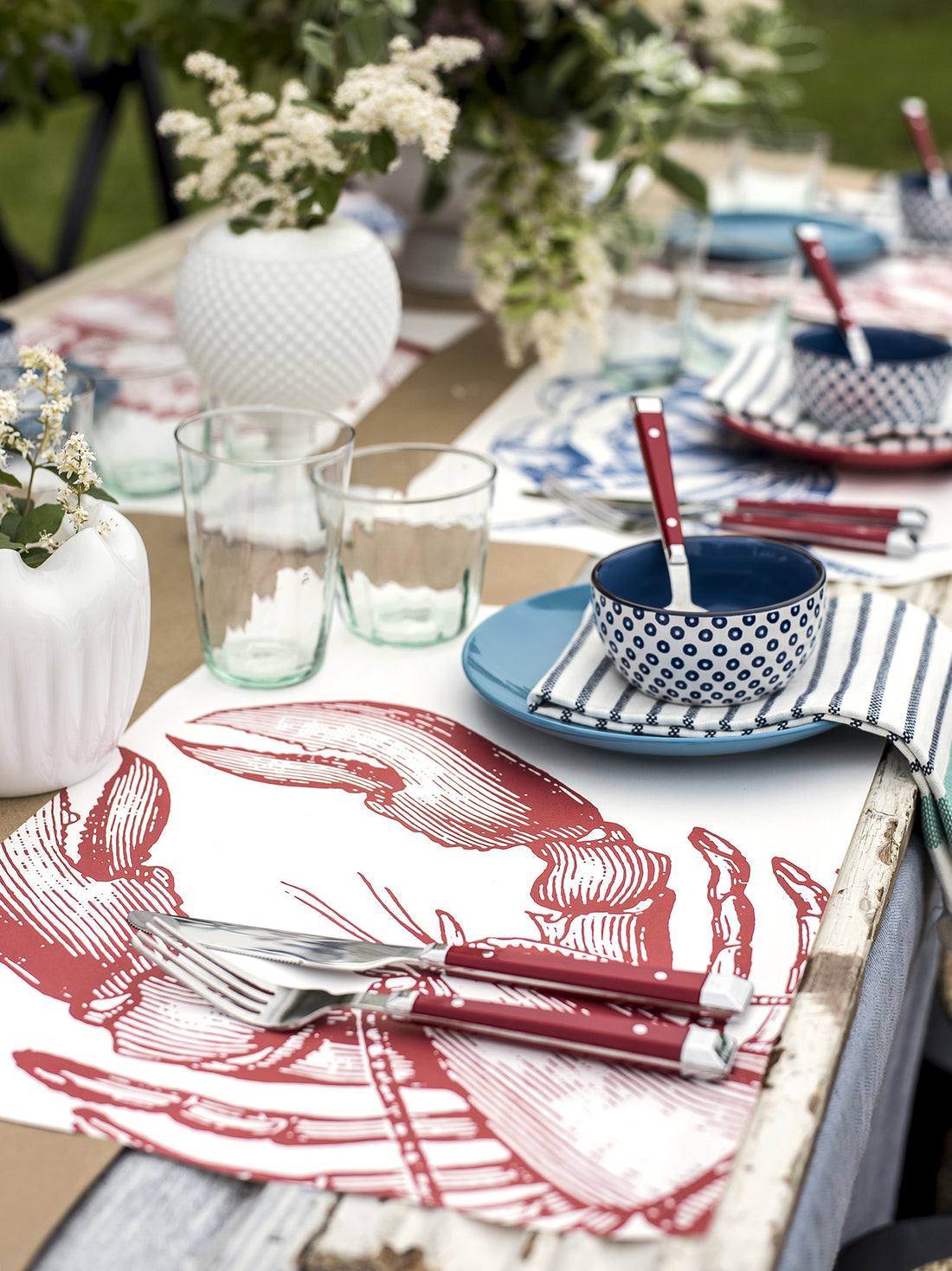 The Lobster Paper Placemat under a nautical-themed table setting.