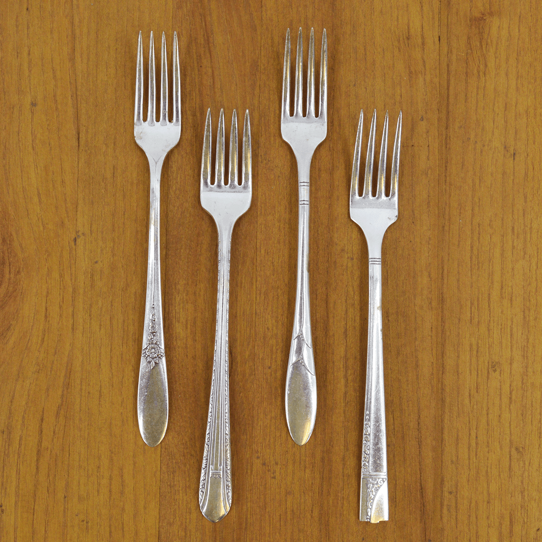 Elegant table setting with mint green plates, Hester &amp; Cook vintage silver-plate long handled salad fork set of four, and white tulips on a marble surface.