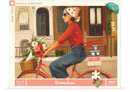 A Brownstones Puzzle of a woman riding a red bicycle with a basket of flowers in front of a building with windows and doors, crafted by Janet Hill, by New York Puzzle Company.