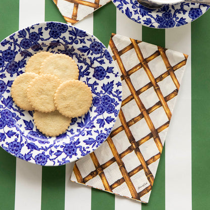 A Bamboo Lattice Guest Napkin on a striped table runner next to a plate of cookies.