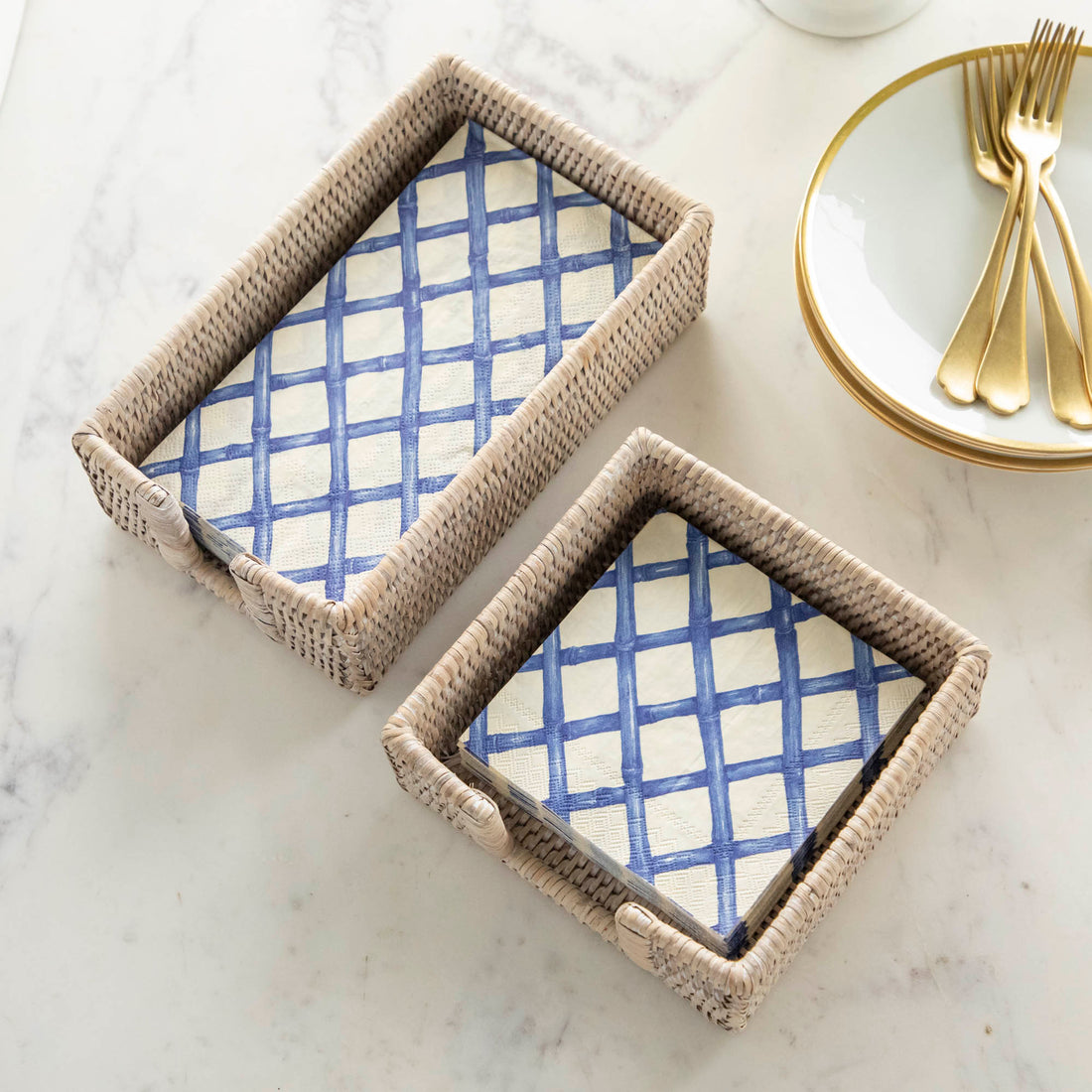 A two Rattan Napkin Holders from Napa Home &amp; Garden on a marble surface.