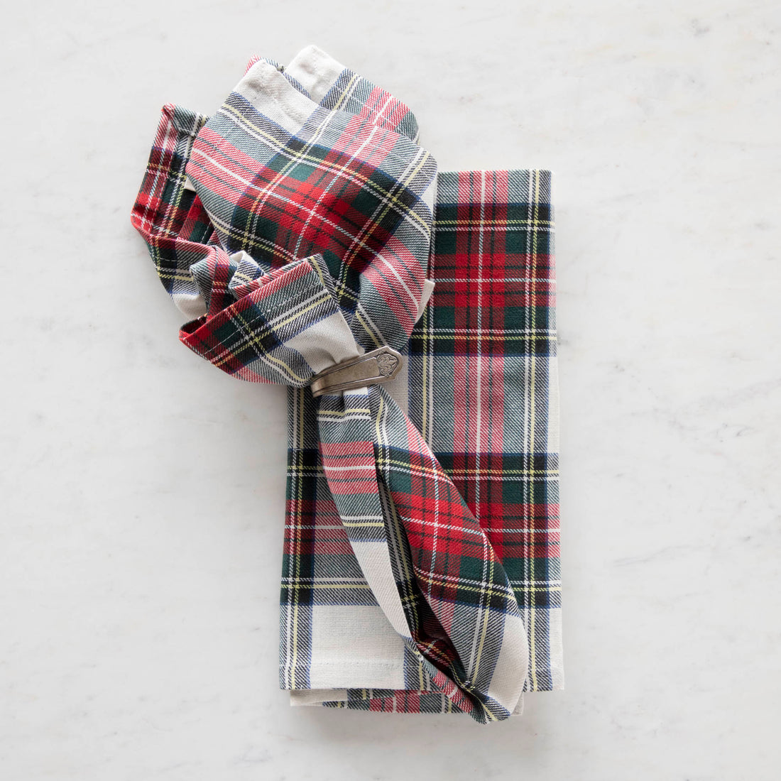 A crumpled Taylor Linen Aberdeen Plaid Napkin lying on a white surface.