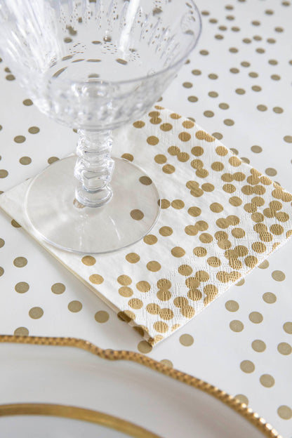 A Gold Confetti Cocktail Napkin under a water glass in an elegant place setting.