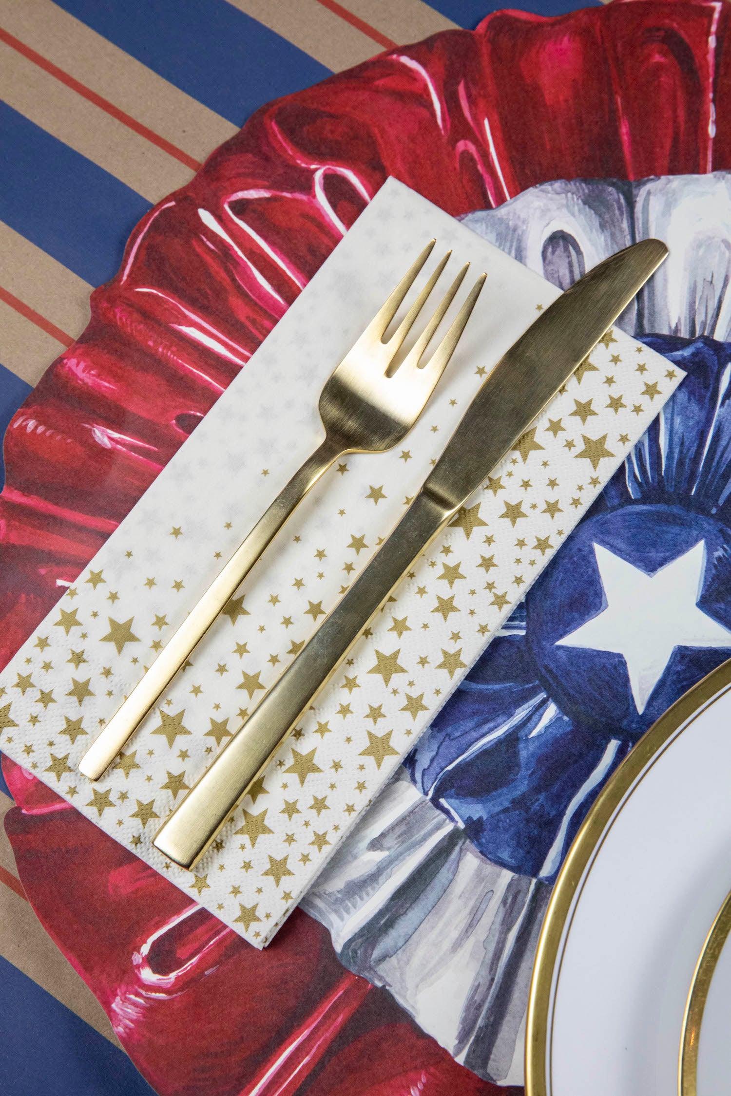 A Shining Star Guest Napkin under the fork and knife of a patriotic place setting.