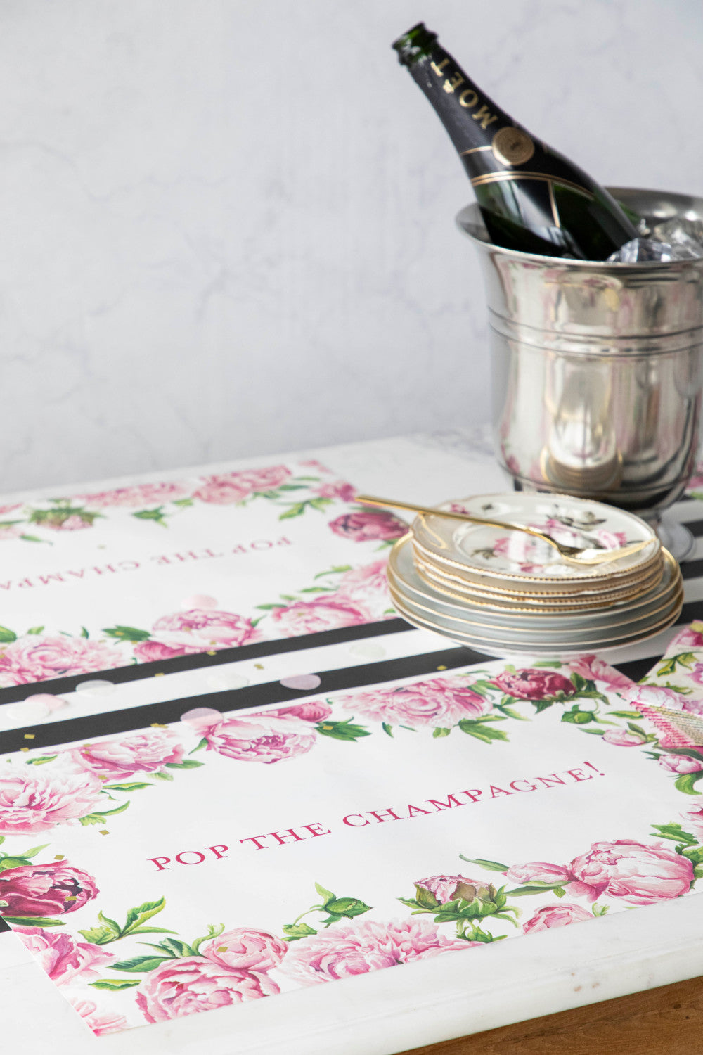 The Peony Personalized Placemat under a festive table setting, with "POP THE CHAMPAGNE!" printed in deep pink.