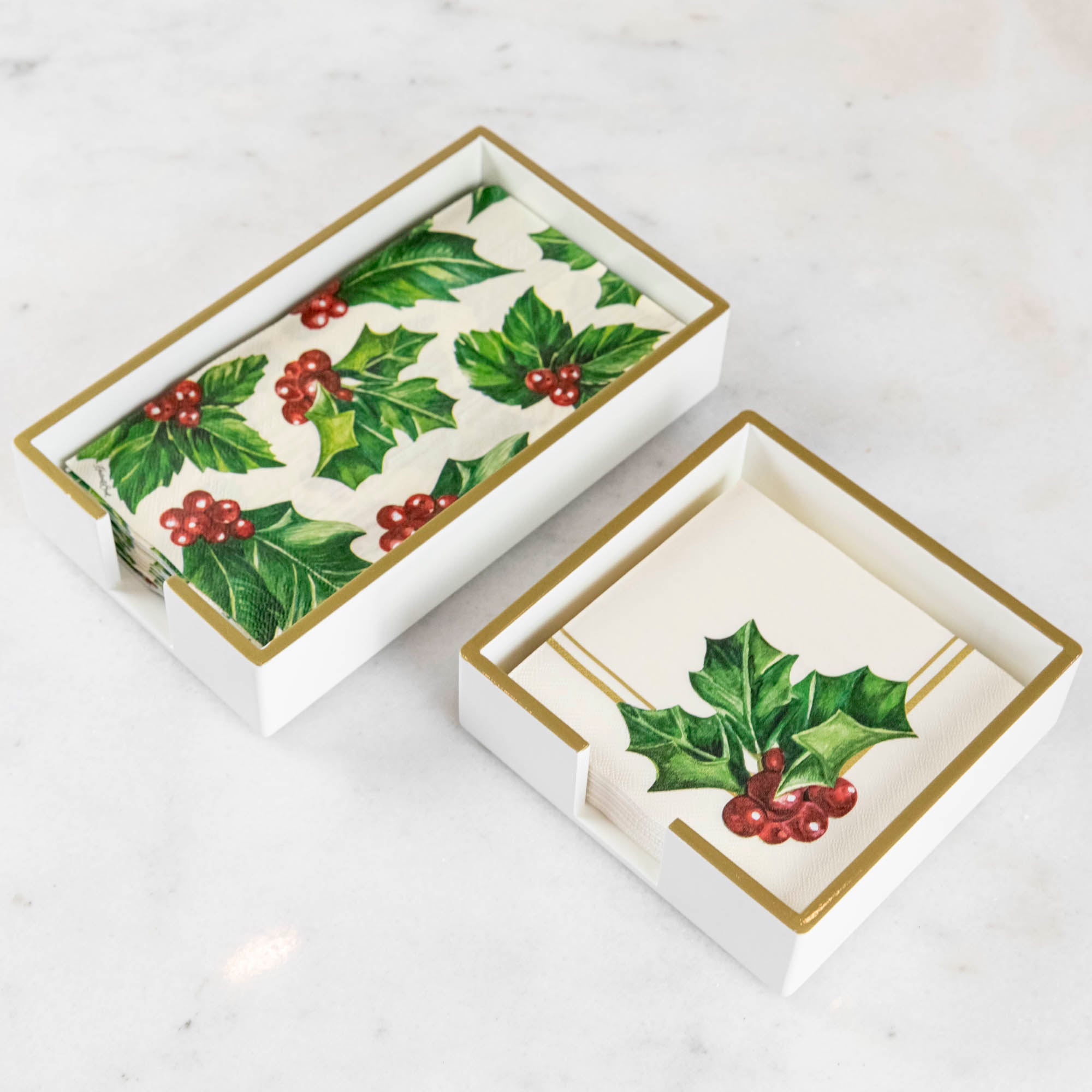 A lacquered wood holder for beverage and guest napkins, featuring a white color with gold trim and a napkin inside.