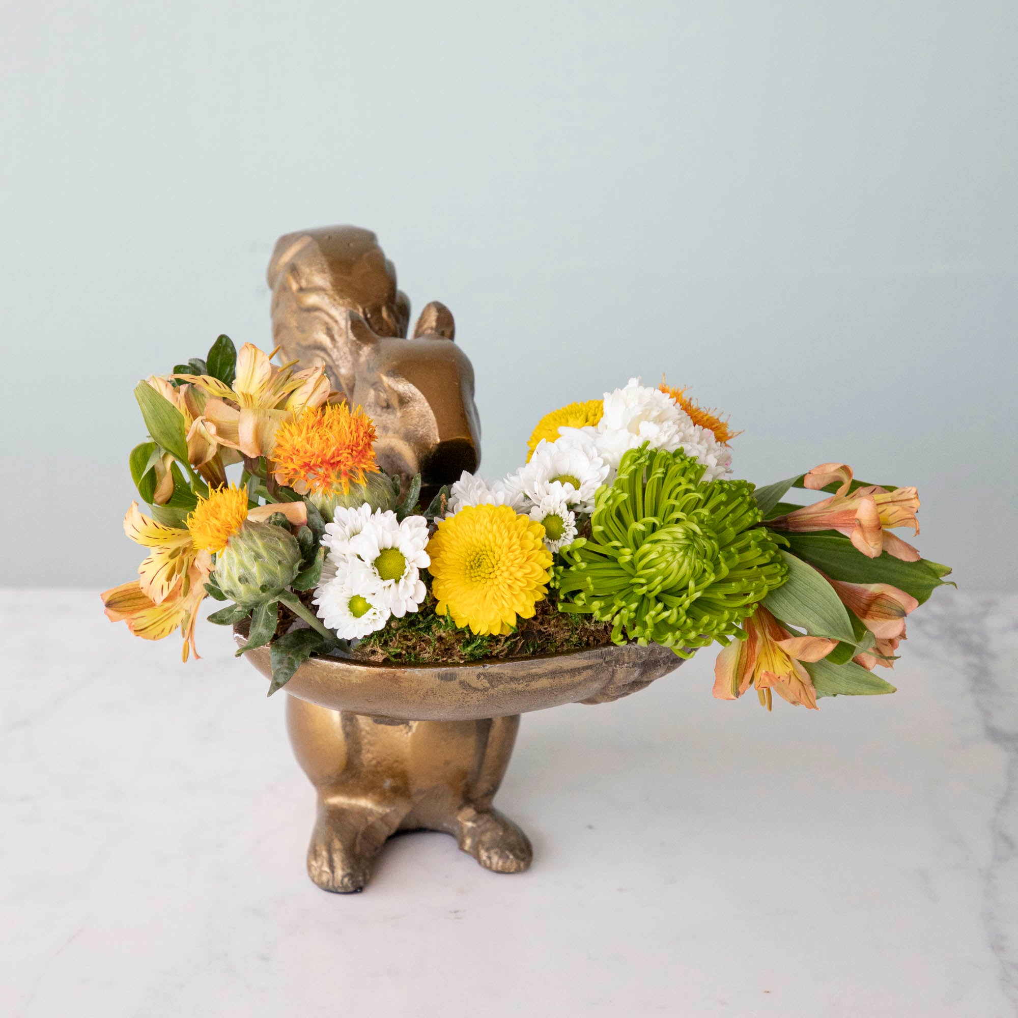 A bronze Accent Decor squirrel holding a bowl of flowers.