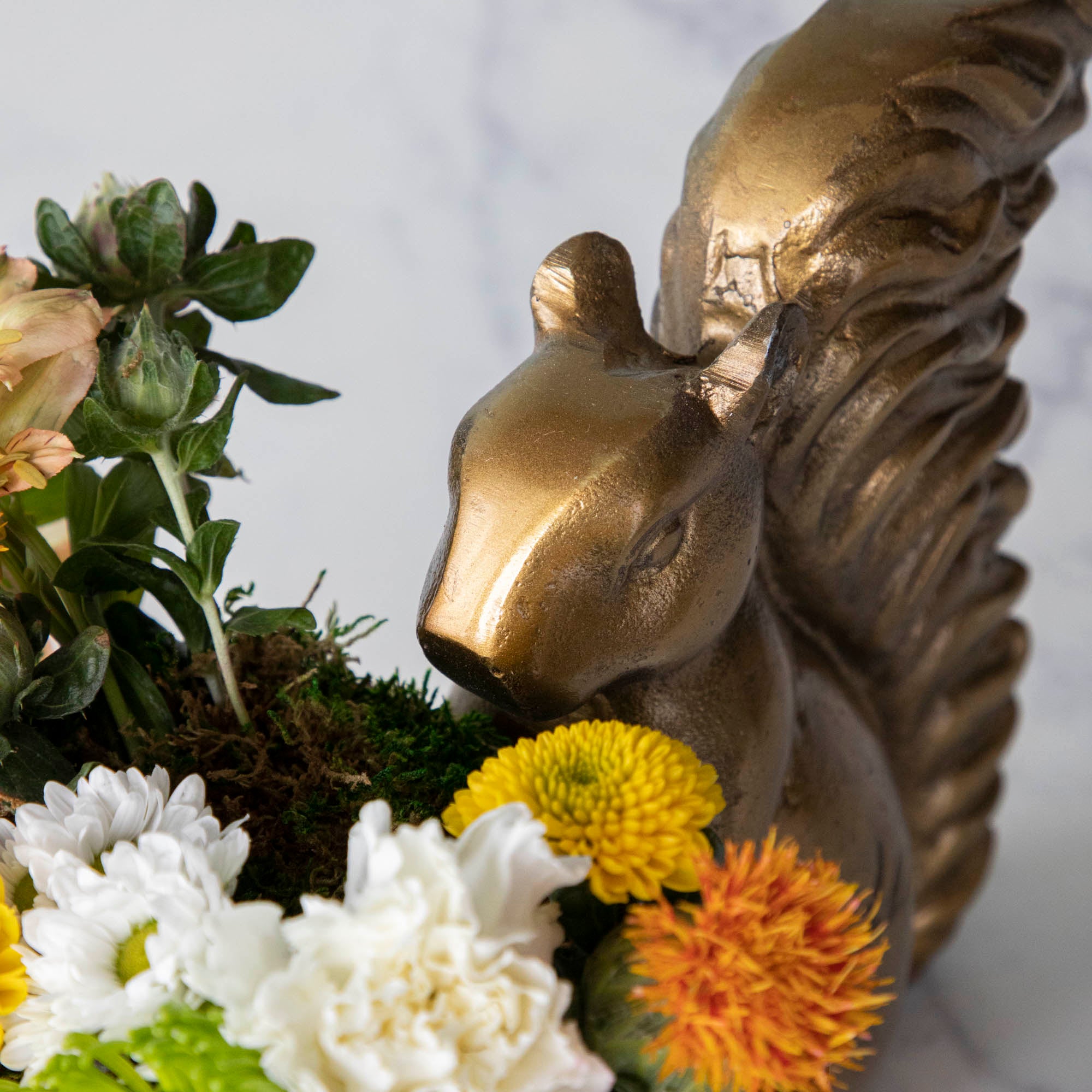 A bronze Accent Decor squirrel holding a bowl of flowers.