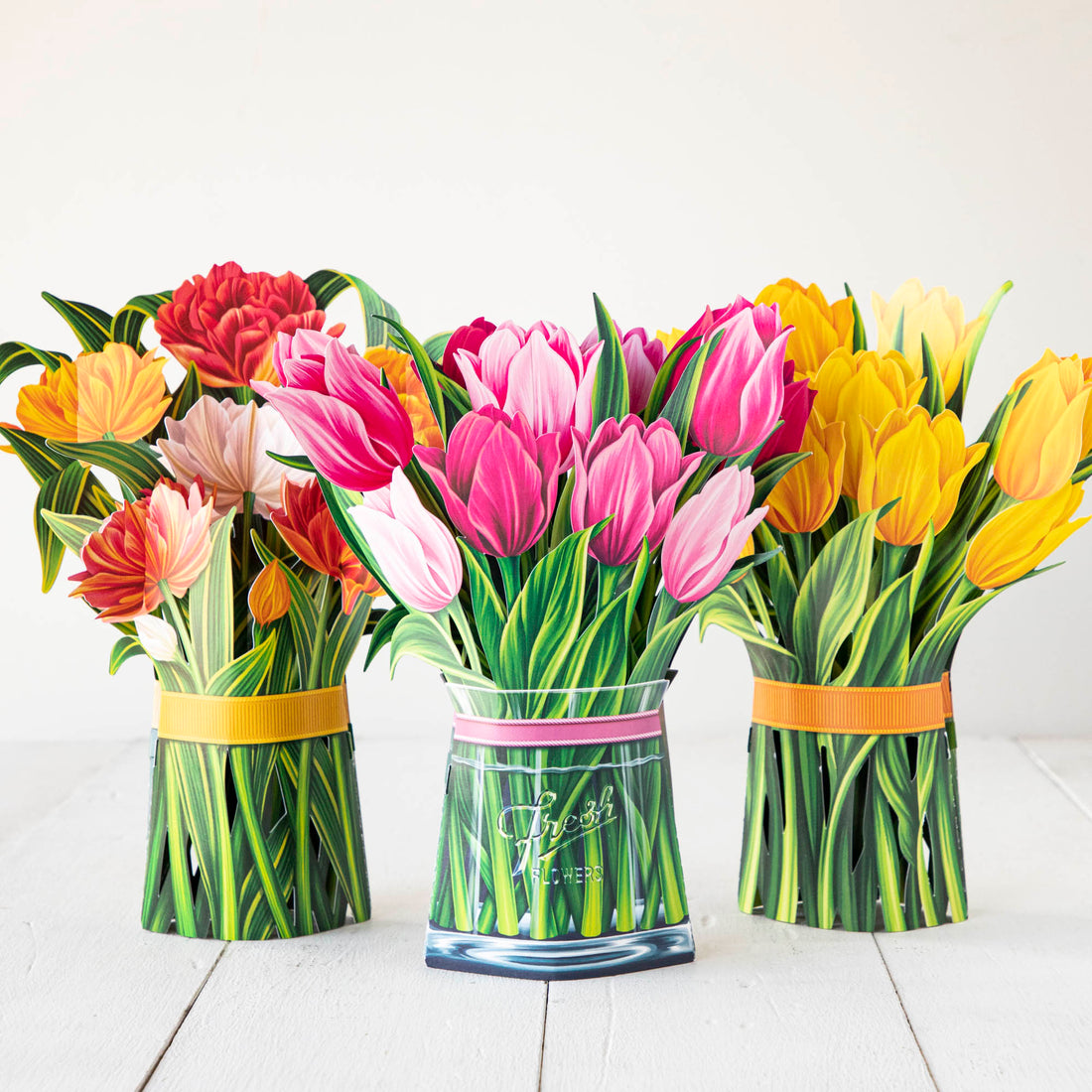 Colorful Fresh Cut Paper Tulip Pop Up Flower Bouquets arranged in vases on a white table.