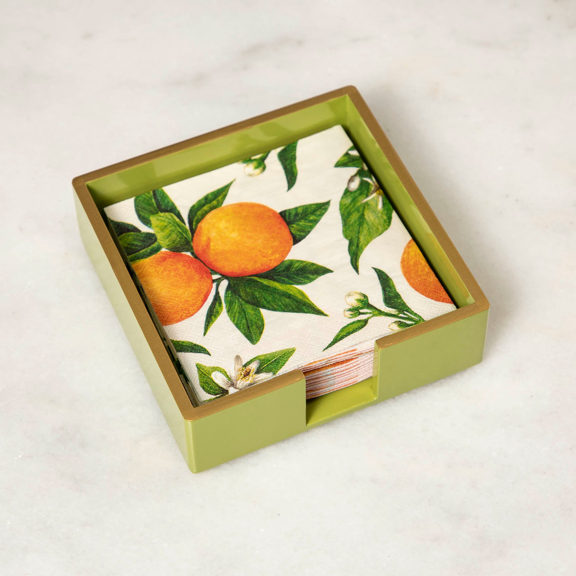 A green lacquered wood beverage napkin caddy with gold trim, featuring a napkin with an orange pattern.