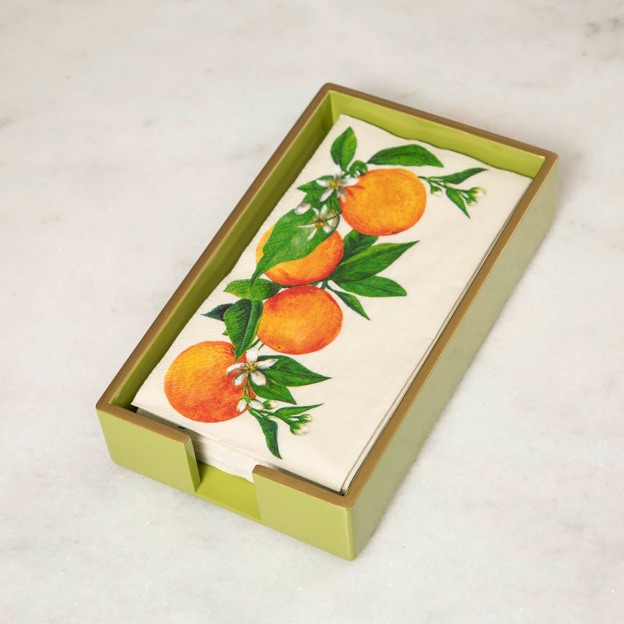 A green lacquered wood beverage napkin caddy with gold trim, featuring a napkin with an orange pattern.