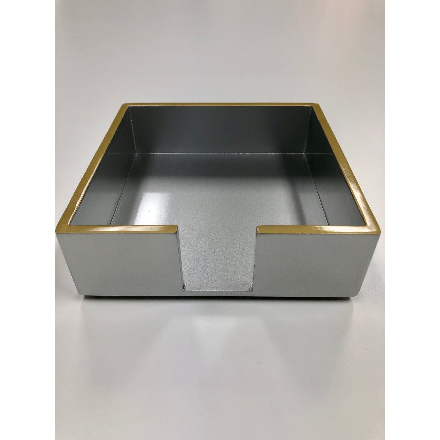A silver lacquered cocktail napkin holder with gold trim.