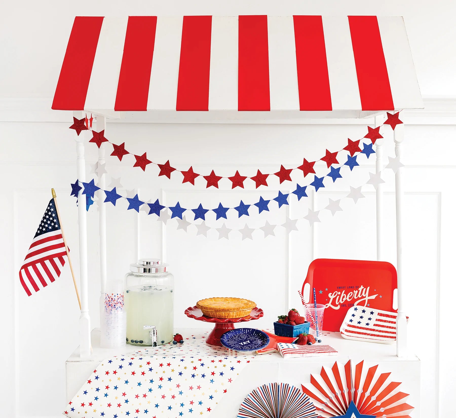 A patriotic lemonade stand with red white and blue stars strung between the poles.