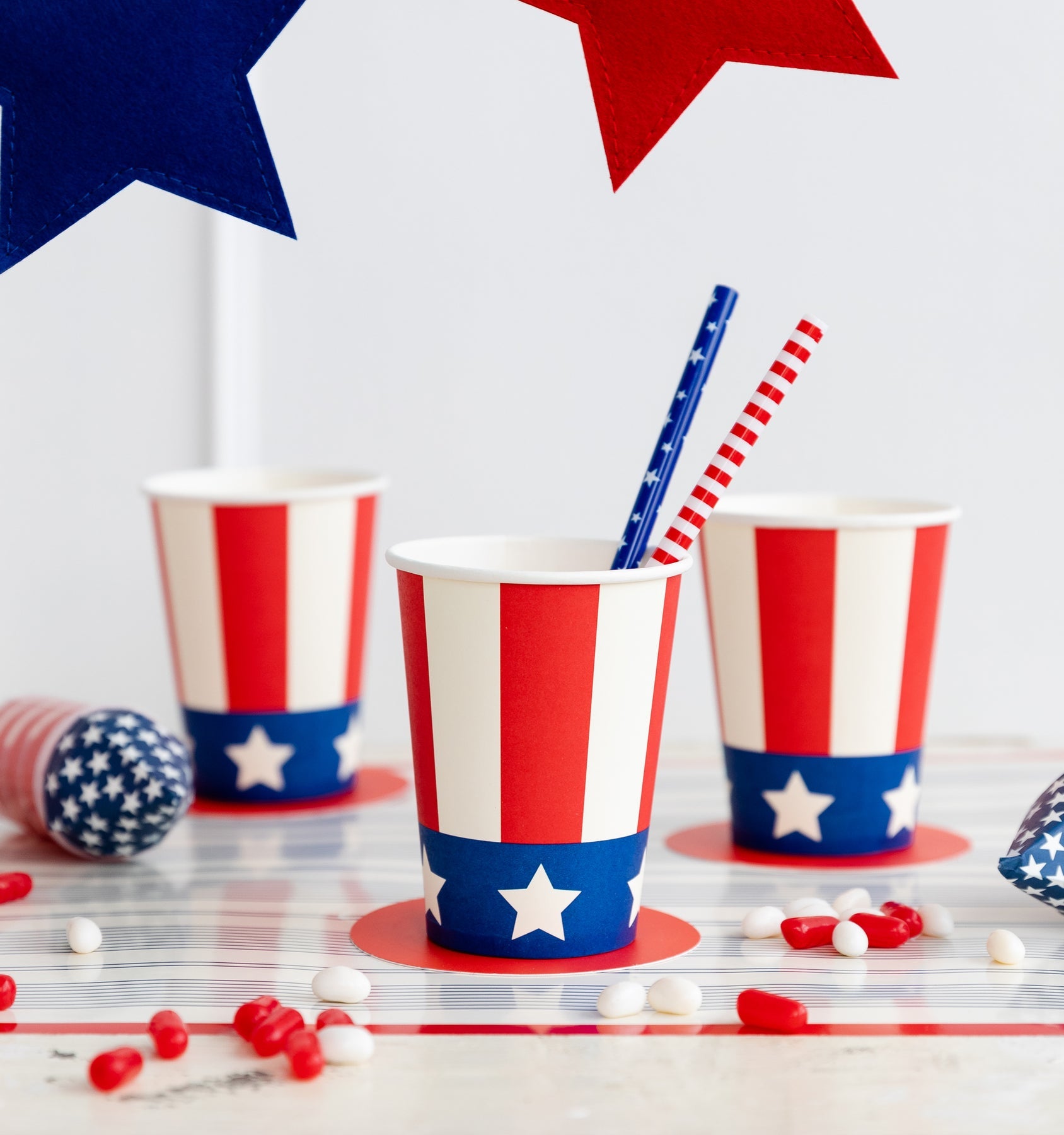 Paper cup with red and white stripes and a blue band at the bottom with white stars.