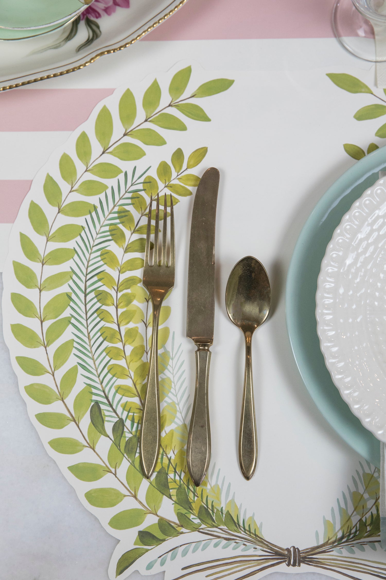 Close-up of the Die-cut Seedling Wreath Placemat under an elegant springtime place setting, showing the leafy artwork in detail.