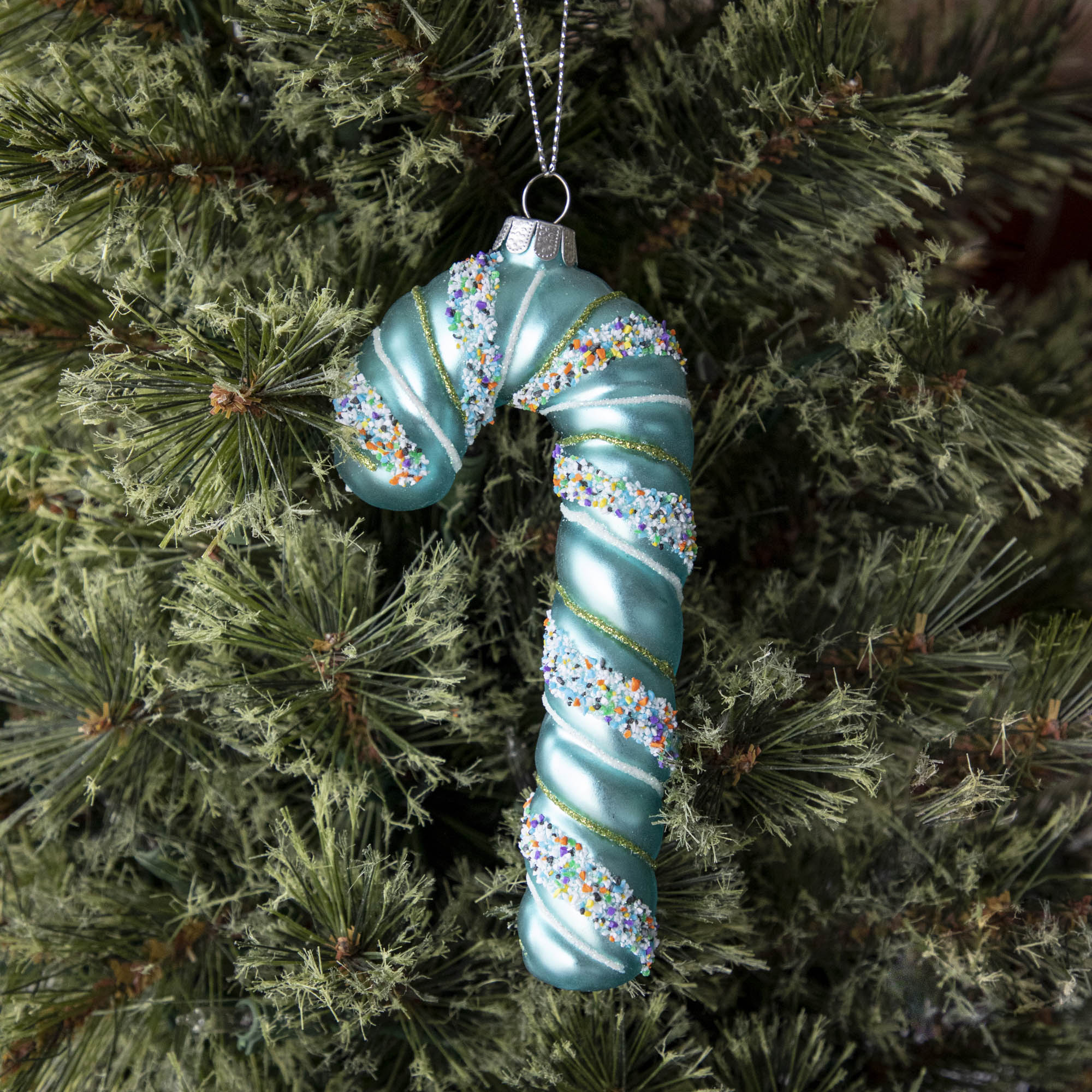 Four festive Glitterville candy cane ornaments on a marble table.