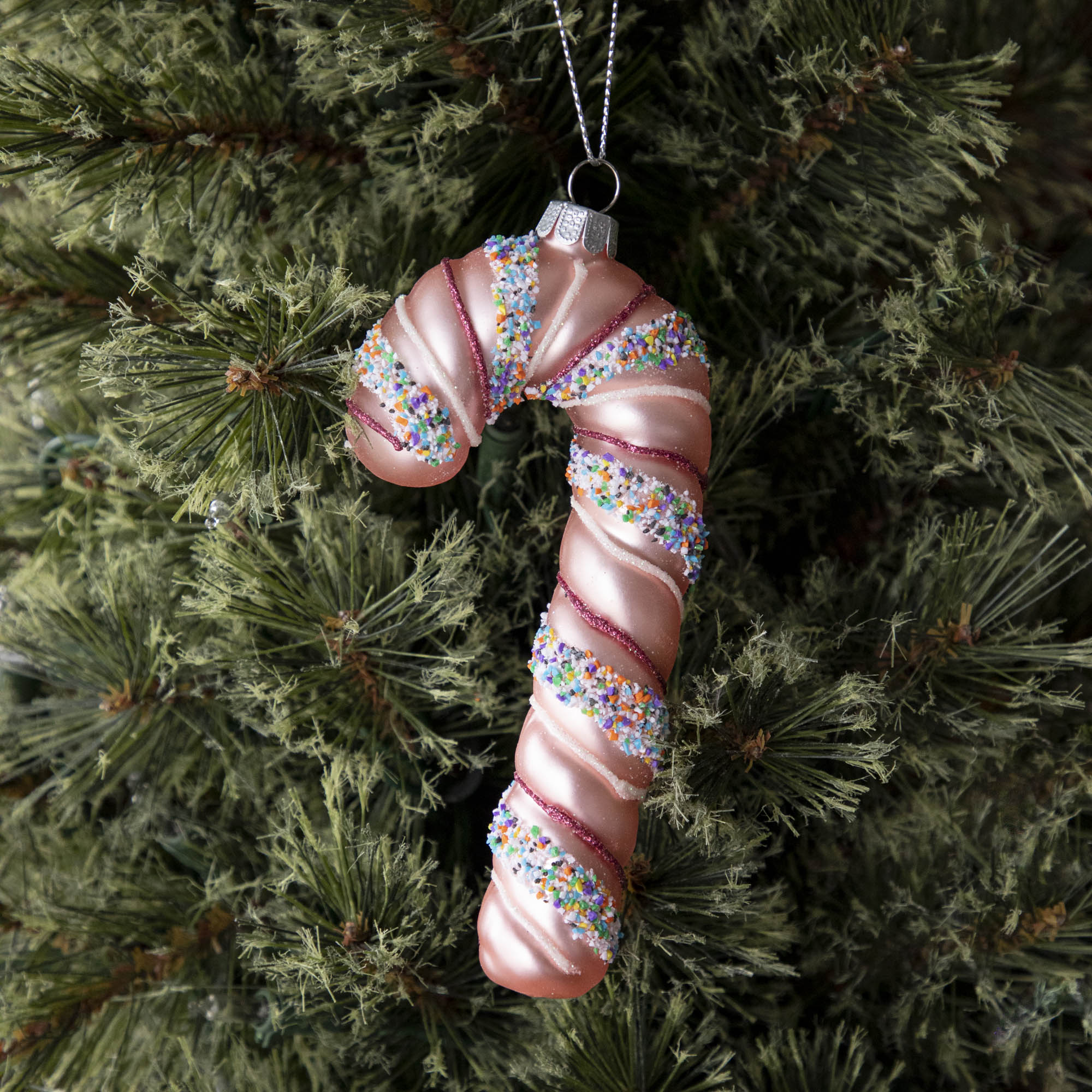 Four festive Glitterville candy cane ornaments on a marble table.
