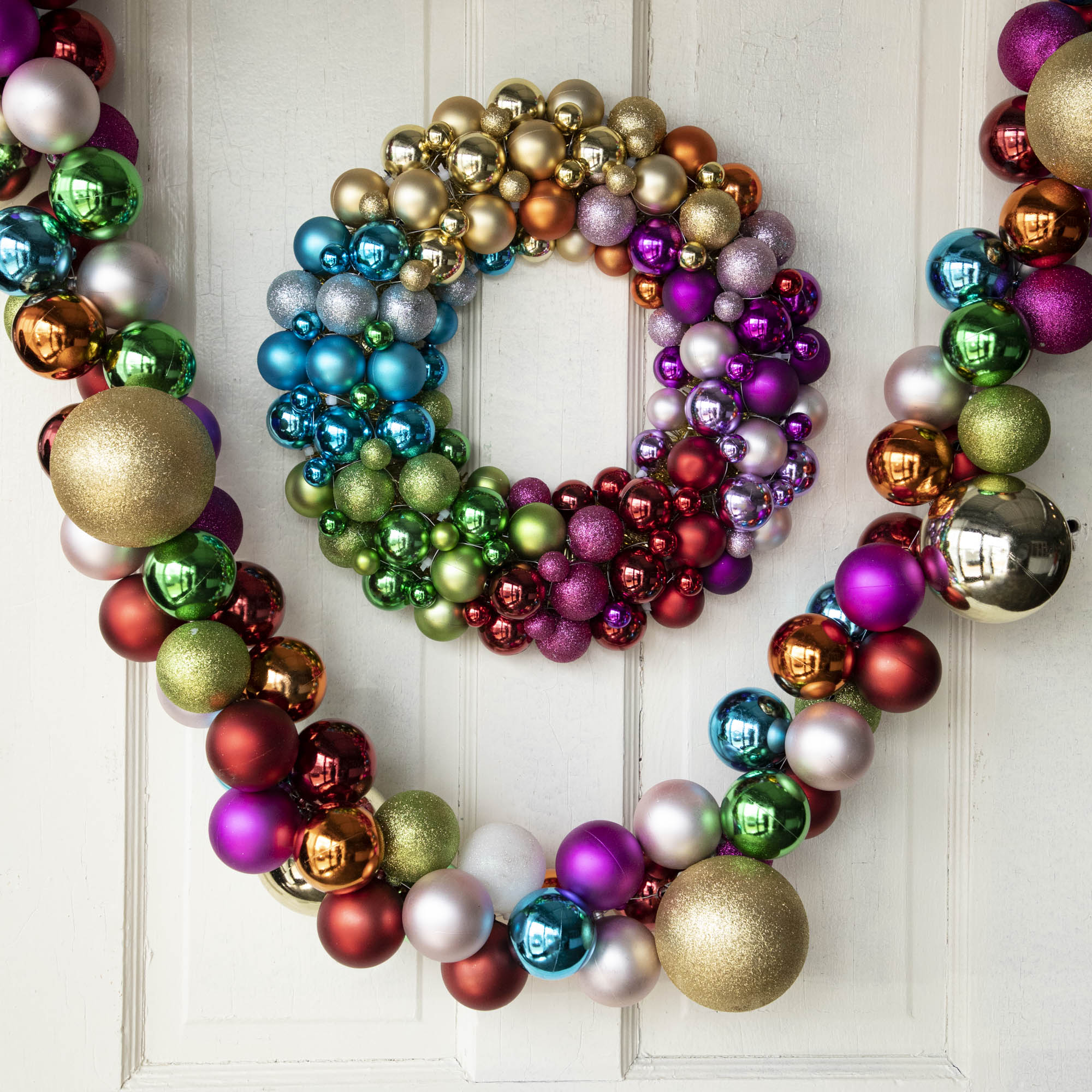 A multicolored wreath made of glass ornaments on a door.