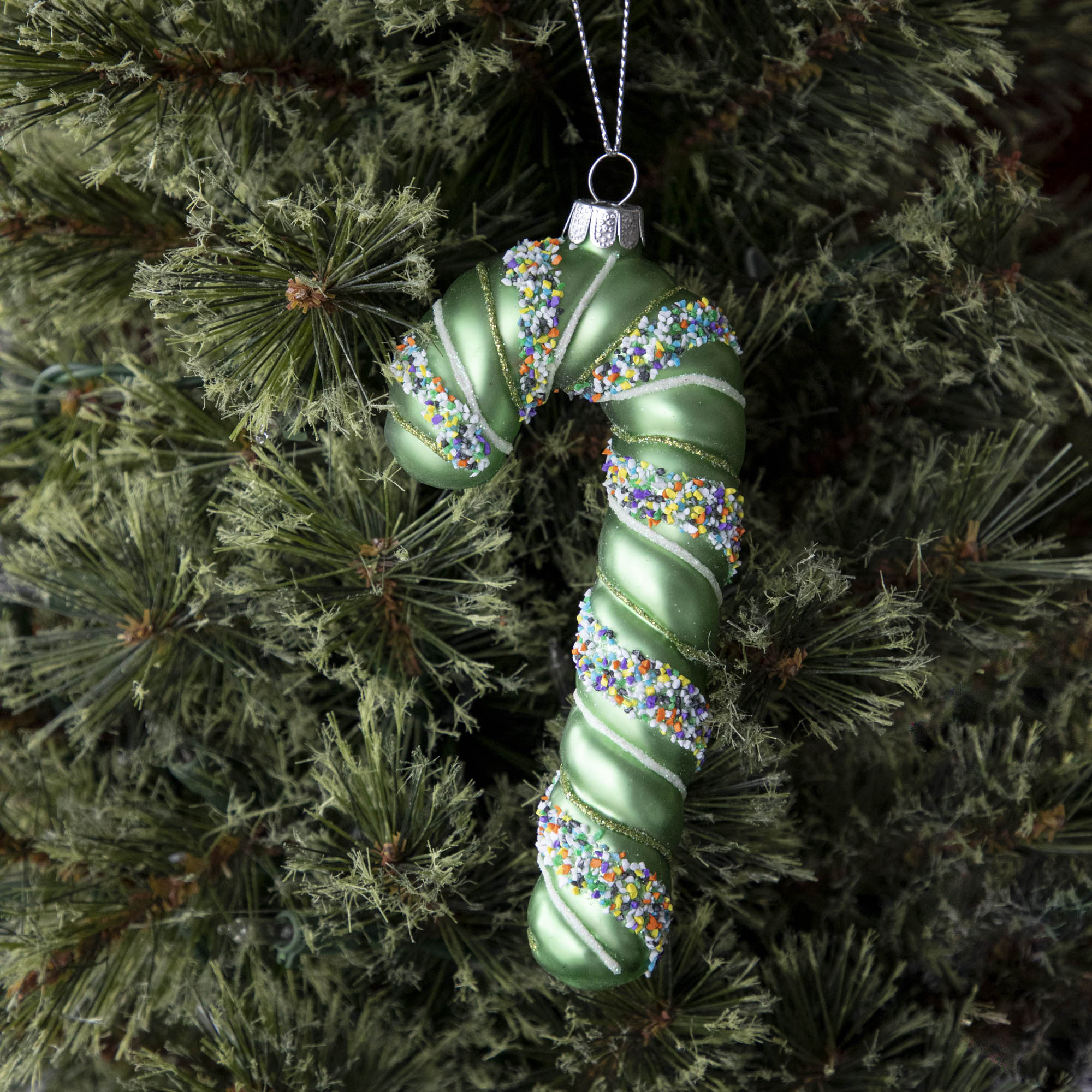 Four festive Glitterville candy cane ornaments on a marble table.