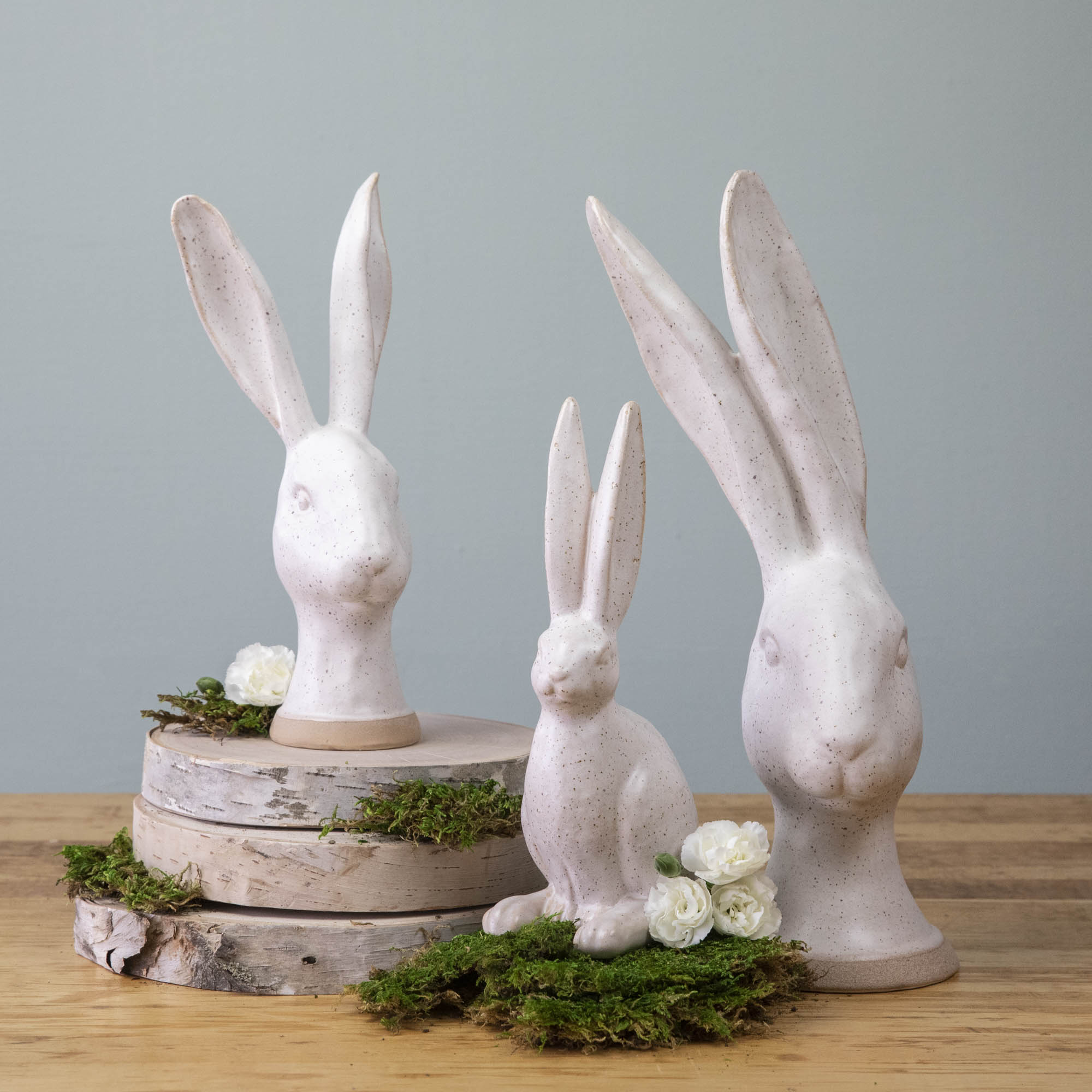 Three enchanting HomArt Matte White Ceramic Hares, ceramic rabbit heads on top of a wooden table.