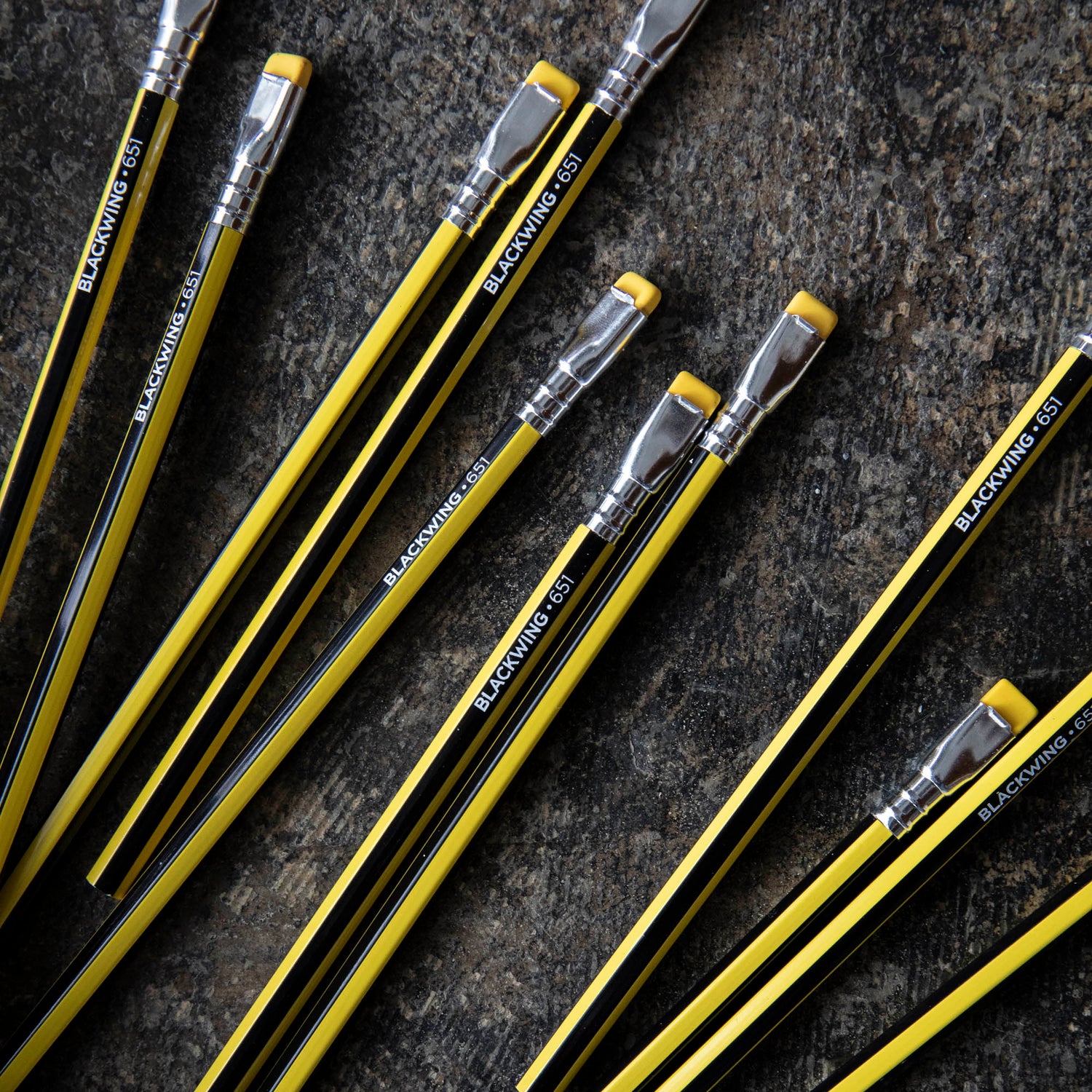 A collection of Blackwing Volume 651- Tribute to Bruce Lee pencils, one sharpened, arranged diagonally on a dark background, reminiscent of Bruce Lee&