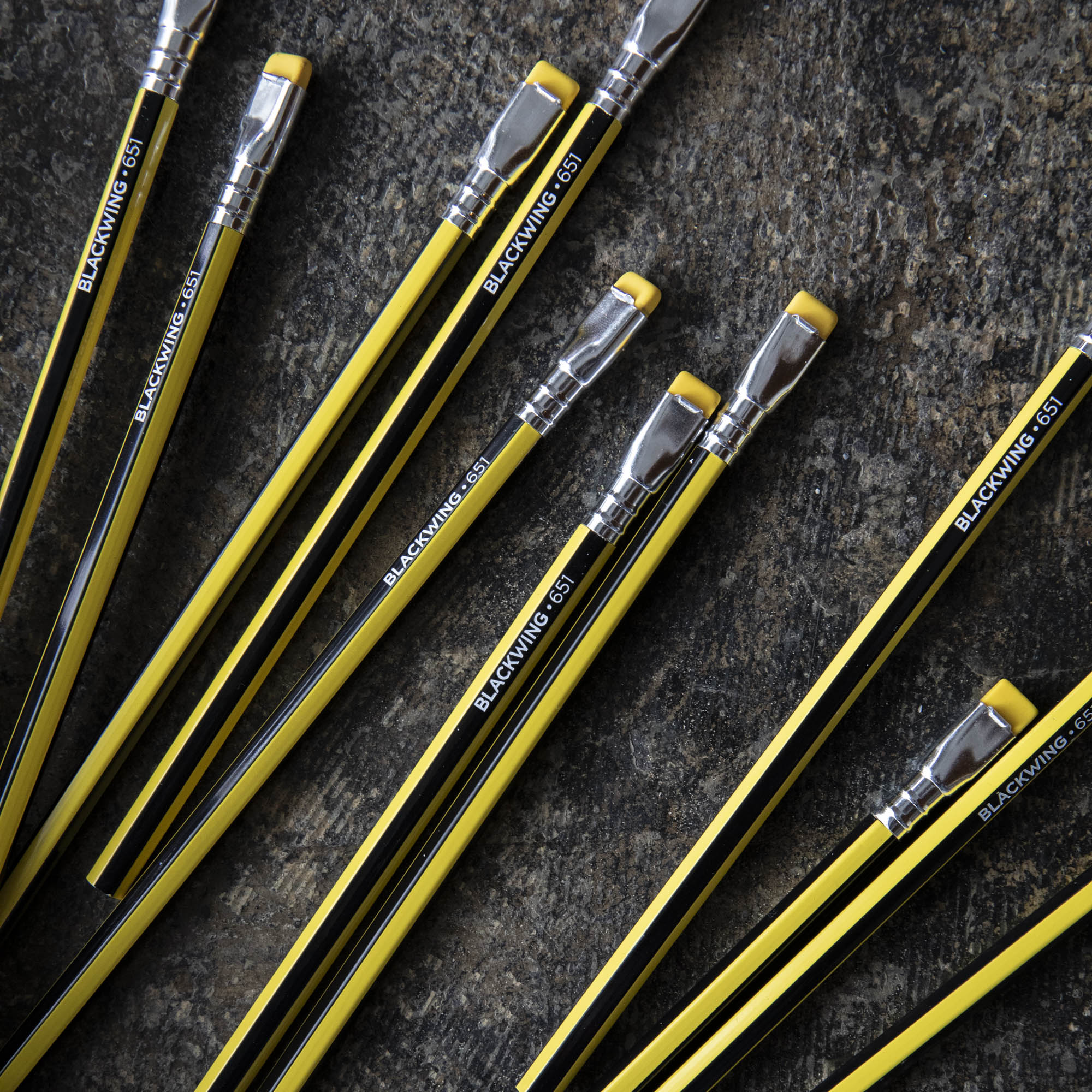 A collection of Blackwing Volume 651- Tribute to Bruce Lee pencils, one sharpened, arranged diagonally on a dark background, reminiscent of Bruce Lee&