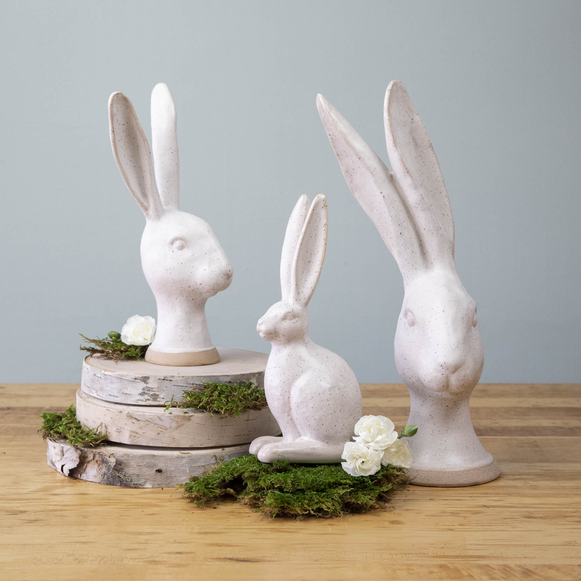 A group of enchanting Matte White Ceramic Hares by HomArt on a wood surface.